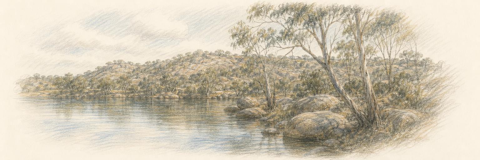 A wide view of Lake Sambell in Beechworth, still water on the left, granite boulders and gum trees along the shore, and wooded uplands behind.